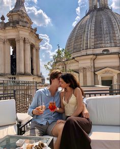 a man and woman sitting on top of a couch next to each other eating food