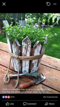 an old wooden bucket filled with flowers and gardening tools