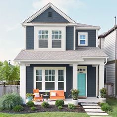 a blue house with white trim and two orange chairs on the front lawn in front of it