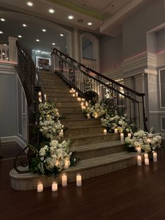 candles are lit on the steps leading up to an elegant staircase decorated with flowers and greenery