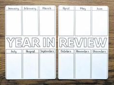 two calendars with the words year in review written across them on top of a wooden table