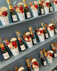 several bottles of champagne and strawberries in buckets on shelves with blue wall behind them