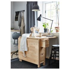 a wooden table with a lamp and some plants on it in front of a window