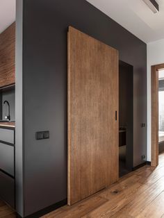 an open door in the middle of a room with wood floors and black painted walls