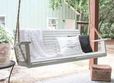 a white porch swing with pillows on it