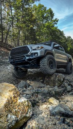 the truck is driving on rocks in the woods