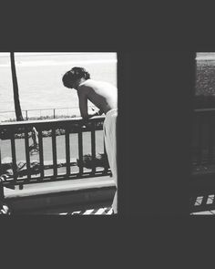 a man standing on top of a balcony next to the ocean