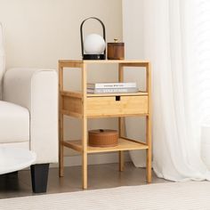 a small wooden shelf with books on it next to a white couch