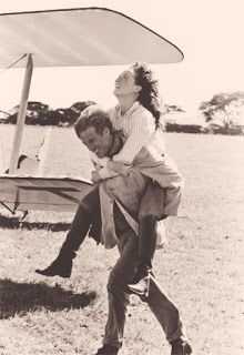 a man carrying a woman on his back in front of an airplane