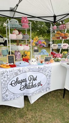 a table covered in lots of cakes and cupcakes for sale under a tent