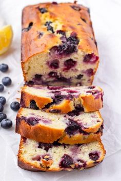 sliced loaf of blueberry bread on top of wax paper next to lemon wedges