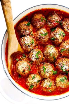 a white bowl filled with meatballs covered in marinara sauce and parmesan cheese