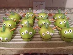 green apples with googly eyes and sticks sticking out of them sitting on a table