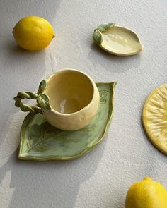 some lemons are sitting on a plate with a cup and saucer next to them