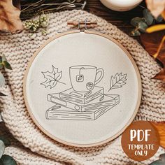 a cross stitch pattern with a coffee cup on top of books and autumn leaves in the background