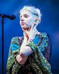 a woman with white hair and piercings standing in front of a microphone