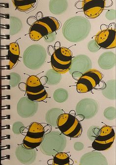 a spiral notebook with yellow and black bees on green circles in front of a white background