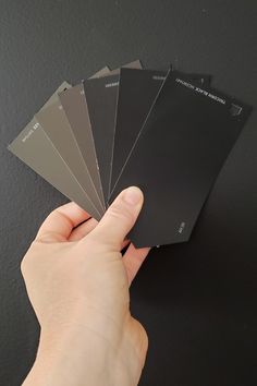 a hand holding five different shades of black and white paper in each one's palm