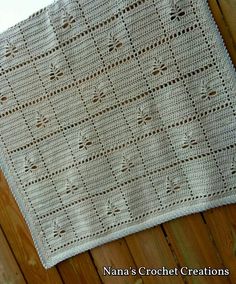 a white crocheted blanket sitting on top of a wooden floor