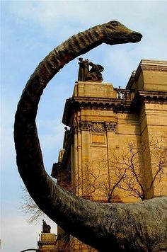 a large dinosaur statue in front of an old building