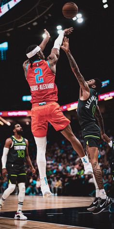 the basketball player is jumping to dunk the ball in front of two other players