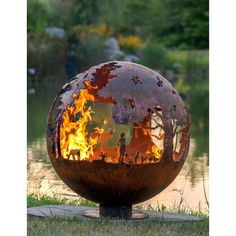 a fire pit sitting on top of a grass covered field next to a lake and forest