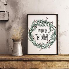 a christmas wreath with the words unto us a child is born on it next to a vase