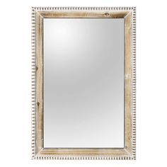 a wooden frame mirror with beading around the edges