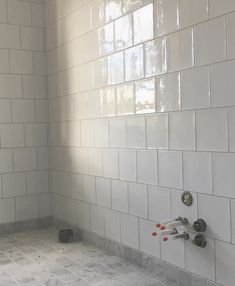 a bathroom with white tiles and no shower curtain