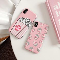 two pink cases with popcorn and cupcakes on them sitting next to a book