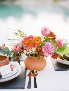 a vase filled with flowers sitting on top of a table next to plates and utensils