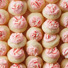 many pink frosted cupcakes with sprinkles and candy canets