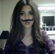 a woman with a fake moustache on her face sitting in front of a couch