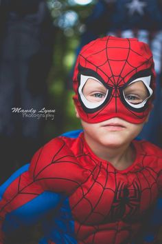 a young boy wearing a spiderman mask with his hands on his hips and eyes closed