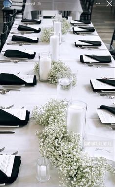 a long table is set with white flowers and black napkins for an elegant dinner