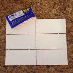 some white tiles sitting on top of a counter next to a blue and white tag