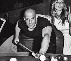 a man and woman are playing pool in a black and white photo with billiards