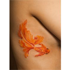 a goldfish tattoo on the side of a woman's stomach, with orange ink