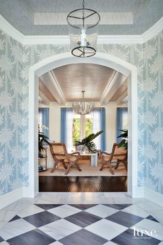 an open door leading to a living room with two chairs and a chandelier