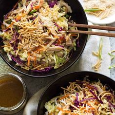 two black bowls filled with coleslaw and carrots on top of a table