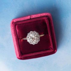 an old diamond ring sits in a velvet box on a blue tableclothed surface