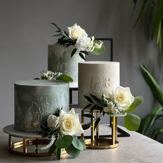 three cakes decorated with flowers and greenery sit on a table next to each other