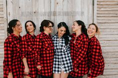 four women in red and black flannel shirts laughing together