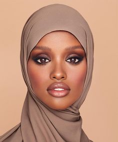 a woman wearing a hijab and makeup looks at the camera with an intense look on her face