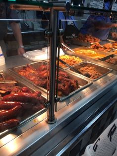 a display case filled with lots of hot dogs and sausages on top of pans