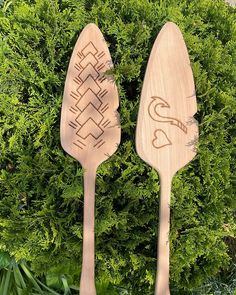 two wooden utensils sitting next to each other on top of green plants and grass