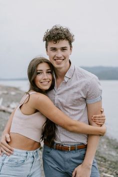 a young man and woman hugging on the beach