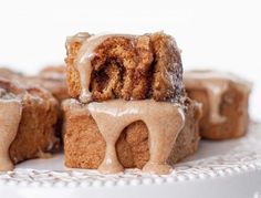 cinnamon roll with icing on a white plate and brown sugar drizzled over the top