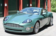 a green sports car parked in front of two garage doors