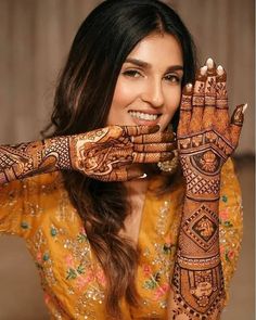 a woman with henna tattoos on her hands and arm, smiling at the camera